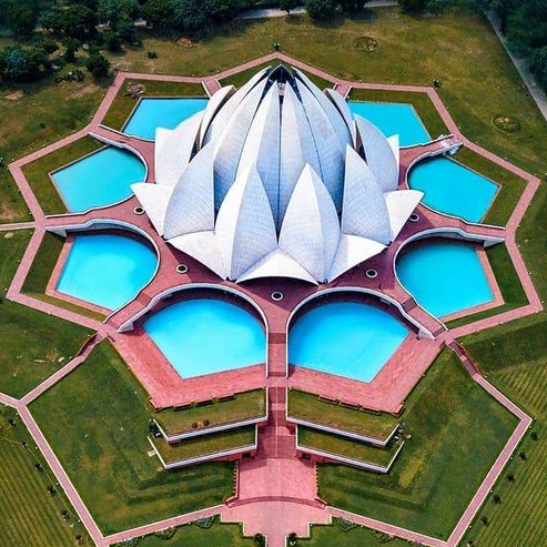 Aerial view of the Lotus Temple in Delhi, India, showcasing its unique lotus flower design and surrounding water pools.