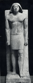 Ancient Egyptian statue of a male figure standing upright, wearing a kilt and broad collar, depicted with a serious expression and a streamlined headdress.