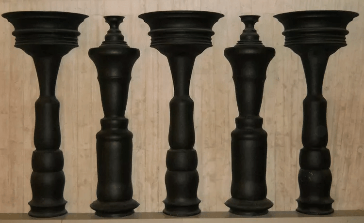 Five black wooden pedestal legs of varying designs, showcasing different shapes and patterns, set against a light wood background.