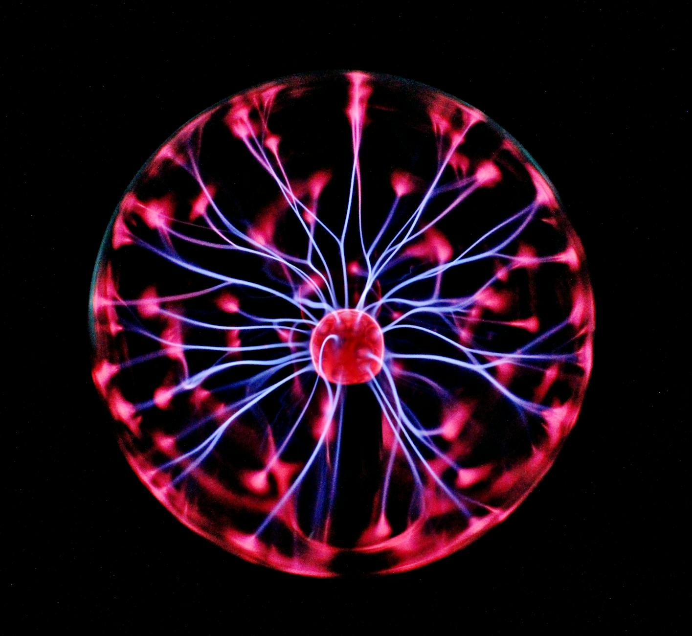 A close-up of a plasma globe emitting vibrant red and blue electric arcs against a black background.