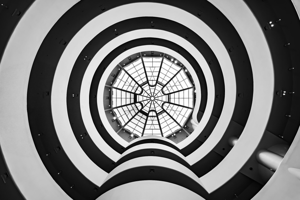 View of the interior spiral structure of the Guggenheim Museum, showcasing a circular skylight and architectural design that emphasizes angles and lines.
