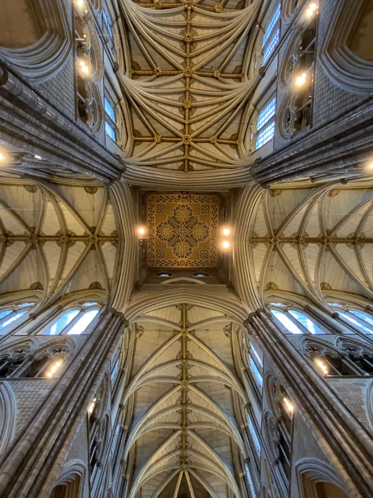 A view of an intricately designed cathedral ceiling showcasing elaborate arches, ornate patterns, and warm lighting.