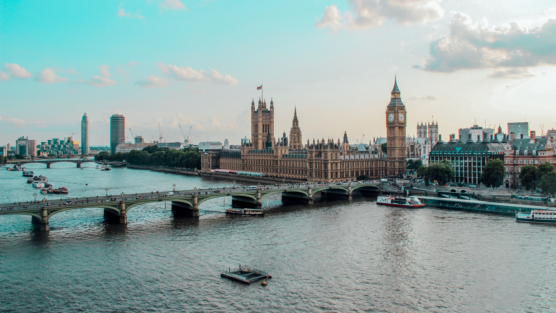 View across the River Thames in London toward the Palace of Westminster and Elizabeth Tower, commonly known as Big Ben, with Westminster Bridge crowded with people crossing the river.